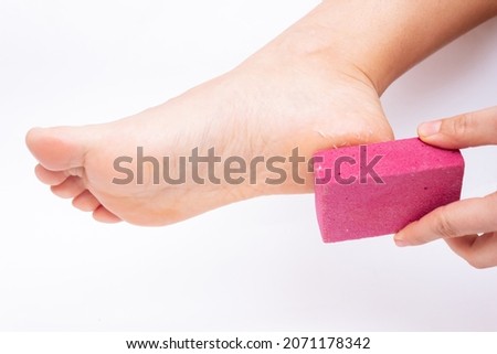 Close-up of a female foot with peeling skin on the heel. A young woman scrubs her foot with a pumice stone isolated on a white background	 Stock fotó © 