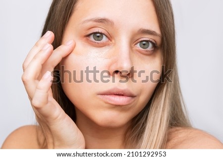 Close-up of a young beautiful caucasian blonde woman applying the tonal foundation for dark eyes. Bruises under the eyes are caused by fatigue, nervousness, lack of sleep, insomnia, stress Stock fotó © 