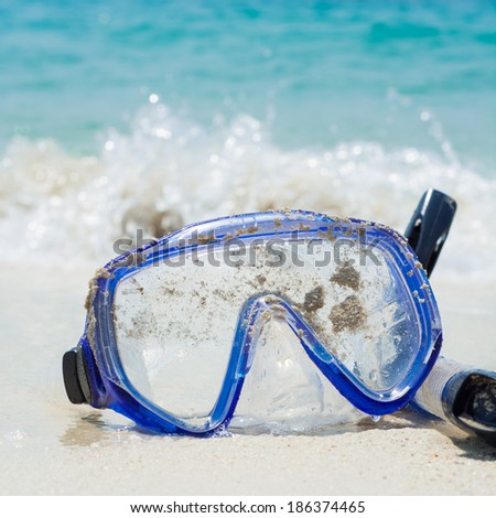 Diving equipment mask on white sand beach.