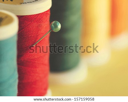 Pin and spools of thread. Colorful composition with a pin  in the foreground.