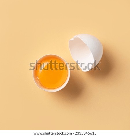 Broken egg into two halves with yolk and shell on a yellow background. Conceptual product mockup for design. Top view and copy space. Photo stock © 