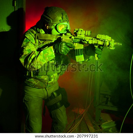 Special forces soldier with gas mask during the night mission (red and green light for underline the atmosphere)
