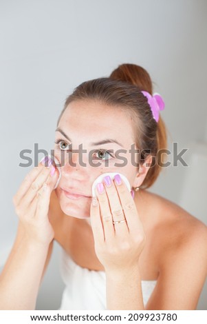 Portrait of young beautiful woman cleaning her face with cotton pads