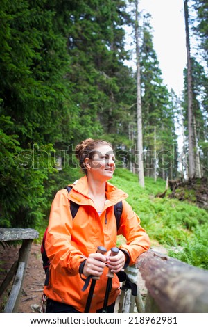Active attractive young woman/female tourist nordic walking outdoors on a forest path, enjoying beauty of nature in national park (colorful image, shallow DOF)