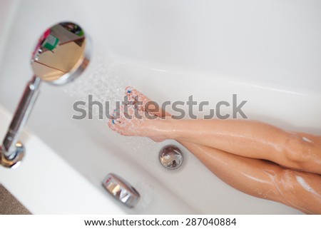 Beautiful young woman taking a shower/hot bath tub and washing hair (rest for her legs)