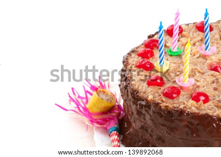 Closeup of a German Chocolate Birthday cake with chocolate frosting, maraschino cherries, vintage candle holders and party blower for children, kids, or adults on white background with room for text