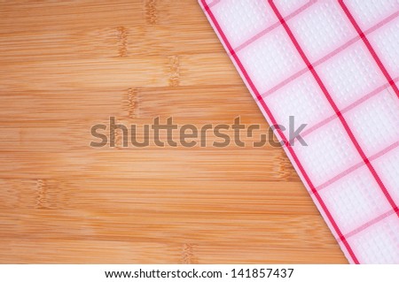 A Checkered Kitchen Towel Laying on Bamboo Cutting Board or Counter Top with Room for your words or text.  Horizontal or Vertical.