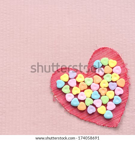 Red Cloth Valentine with Heart Shaped Candies in the center of it, all on a pink cardboard background with room or space for copy, text, words