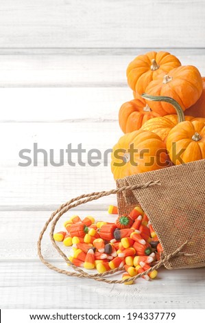 Candy Corn Spilling from Burlap Bag on Rustic White or Gray Wood Board Background with room or space for copy, text.  Vertical