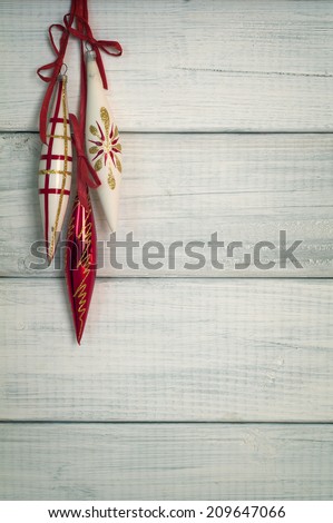 Three Long Vintage Christmas Ornaments Hanging on Rustic White Board Background with Empty Room or Space for copy, text, words.  Vertical still life for card or invitation.  Cyan instagram