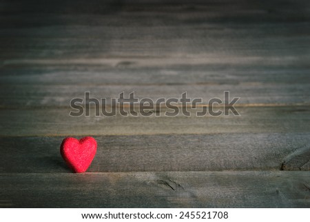 Moody instagram style Valentine red Candy Heart on Rustic Wood Board Background with room or space for copy, text, your words.  Horizontal vignette, simple composition