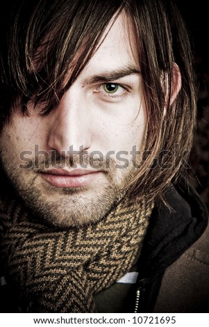 Attractive man wearing a scarf with hair over one eye.