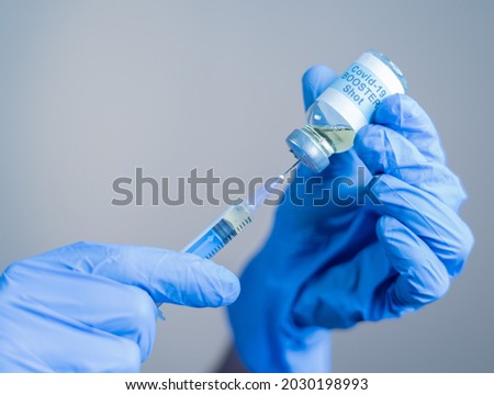 Focus on syringe, close up of doctor or nurse hands taking covid vaccination booster shot or 3rd dose from syringe.