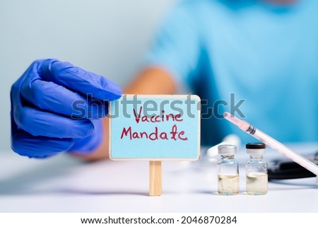 Concept of coronavirus or covid-19 vaccine mandate, showing with doctor hands with gloves by placing sign board next to vaccine shots and syringe.