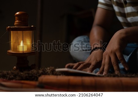 unrecognizable Young student busy reading during night under oil lamp or lantern due to power loss and Poverty - concpet of power cut, blackout, electricity failure during examination. Photo stock © 