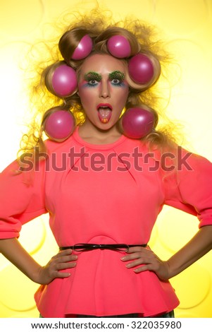 Cheerful girl with bright makeup and hair balls on a yellow background