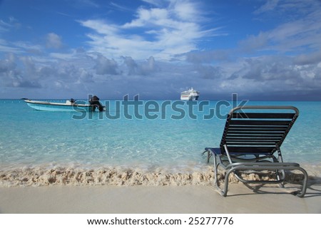 Tropical island beach with lounge chair, cruise boat and fishing boat