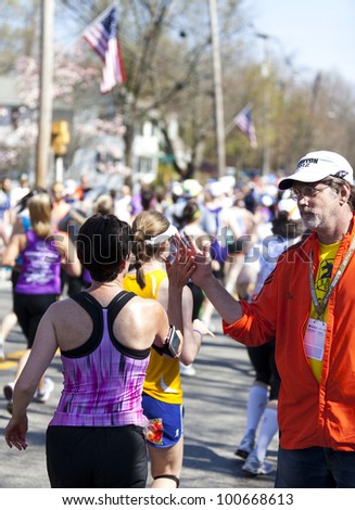 HOPKINTON, USA - APRIL 4: Boston marathon\'s staff member giving high fives to incentive amateur  runners during the race in Hopkinton, Massachusetts, USA on April 16, 2012.
