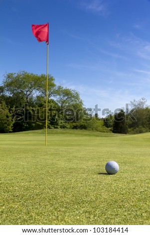Nice golf field with flag and golf ball.