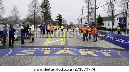 HOPKINTON, USA - APRIL 20: The start line of the Boston Marathon 2015 in Hopkinton, MA, USA a few minutes before the start of the race with staff, police, and locals passing by on April 20, 2015.