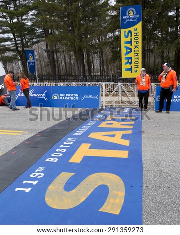 HOPKINTON, USA - APRIL 20: The start line of the Boston Marathon 2015 in Hopkinton, MA, USA a few minutes before the start of the race with staff members, and locals passing by on April 20, 2015.