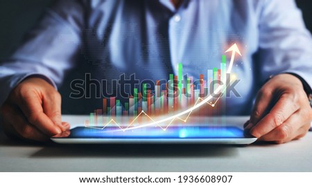 Business strategy development and growing growth plan. Businesswoman holding tablet with  growing virtual hologram of statistics, graph and chart.
