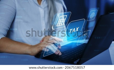 Business Woman using a laptop with digital graphic screen to complete income tax form online. Financial research,government taxes and calculation tax return concept. Tax Time