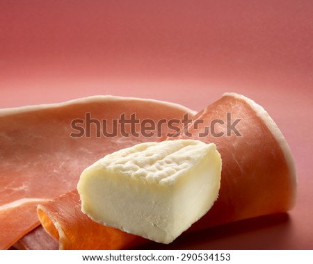 Pieces of cheese and ham on red background