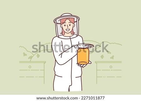 Young woman beekeeper in protective uniform holding jar of honey standing in apiary among flying bees. Girl farmer breeds bees in garden getting organic honey for sale at fair of ecological products