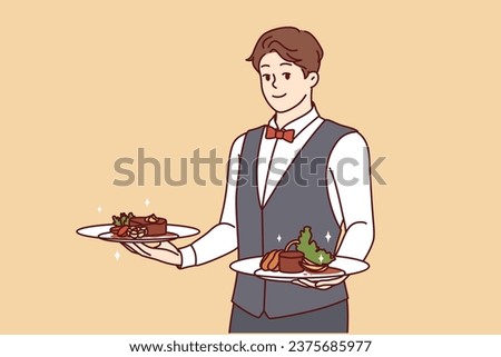Man waiter holds plates of desserts and invites you to go to gourmet restaurant, dressed in vest and bow tie. Guy works as waiter in hotel and takes out food prepared by chef for banquet visitors