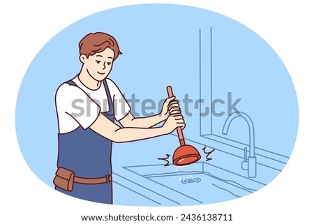 Man plumber uses plunger to clear blockage in sink in kitchen or bathroom. Guy working as plumber is dressed in overalls and is engaged in elimination breakdown associated with debris stuck in pipe