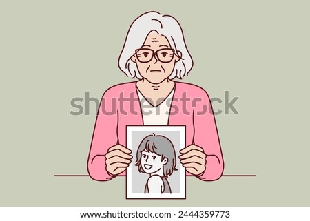 Elderly woman remembers youth, showing portrait from past, and looks at screen with slight sadness. Elderly lady with gray hair shows photo of herself from childhood, wishing she could turn back time.