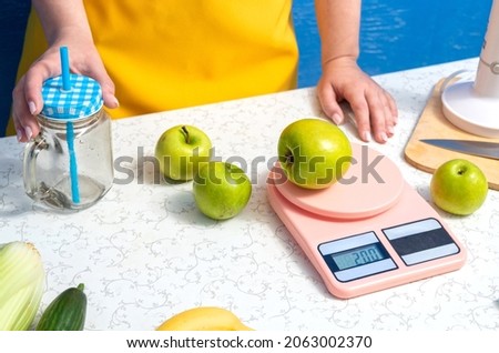 A woman's hand holds a smoothie jar, an apple is weighed on a scale, other apples are on the table. Selective focus. Photo stock © 