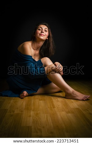 elegant female in dark room relaxing on the floor