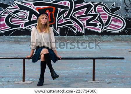 Blonde school girl sitting in front of graffiti wall