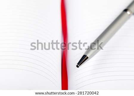 silver pen on opened notebook with red string