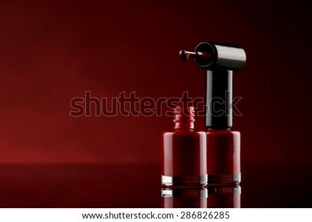 red nail polish on glass table with red background