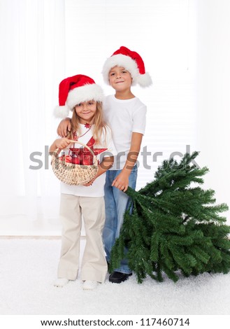 Kids wearing santa hats preparing to decorate the christmas tree - getting the props together