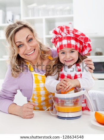 Happy woman and child making fresh orange juice in the kitchen