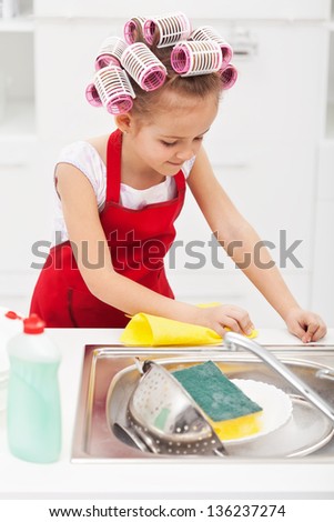 Little girl cleaning the kitchen - wiping the sink area, wearing big hair curls