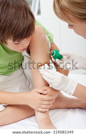 Health care professional taking care of a little boy leg injury - closeup