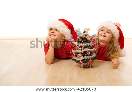 Happy kids with santa hats laying on the floor - isolated with copy space