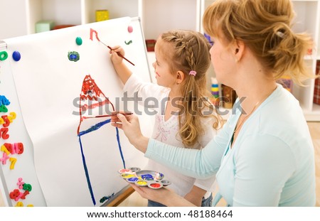 Little girl painting on a large sheet together with her mother