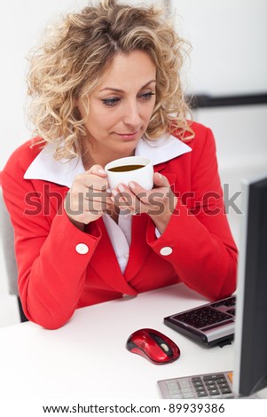 Morning coffee in the office - woman having a cup and checking the news or mail