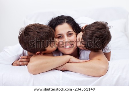 Happy mother kissed by her loving little boys in a tender family moment