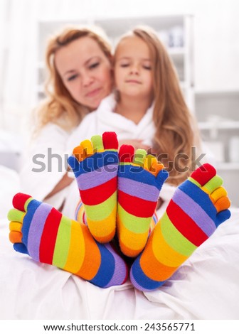 Woman and little girl wearing funny socks - cuddling after bath time