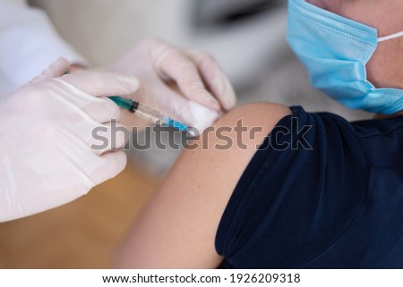 Covid vaccine injection by doctor at hospital. Doctor making injection vaccination patient to prevent pandemic of the disease, flu or influenza virus in clinic