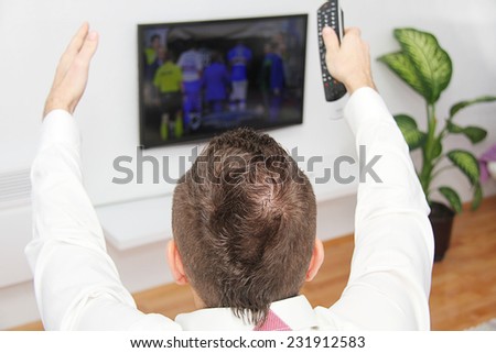 Young man sitting on the couch watching a football game on tv