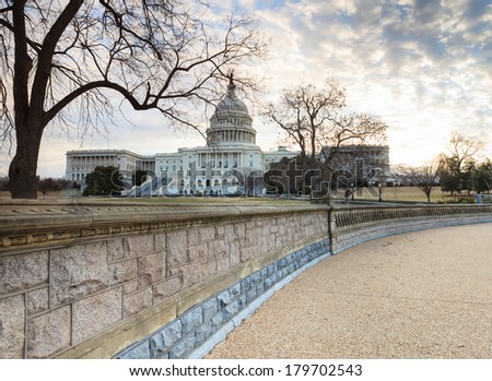 The US Capitol building as seen from the stone retaining wall in Washington DC at sunrise.