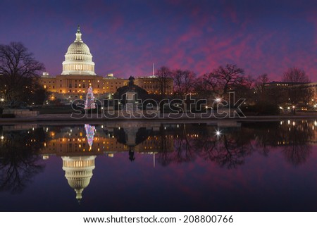 US Capitol illuminated in the pre-dawn blue hour and mirrored in the waters of the reflecting pool in Washington, DC.